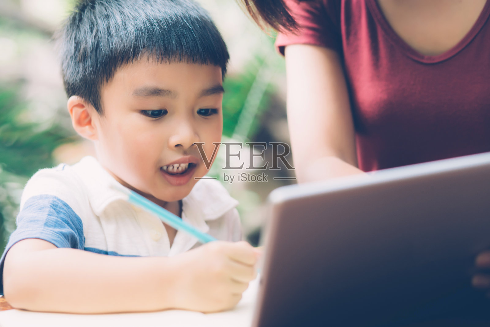 儿子用数码平板电脑进行学习，与母亲一起上网学习，从家里教育，家庭娱乐，妈妈教儿子和作业与技术，生活理念。照片摄影图片