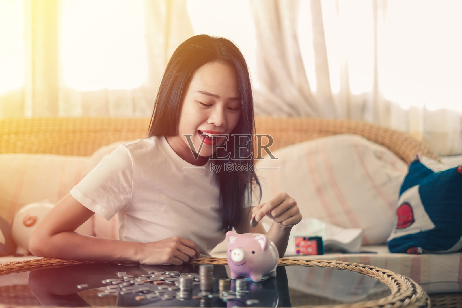 亚洲美丽的女人是微笑和手把硬币放入存钱罐，金融或储蓄的概念。照片摄影图片