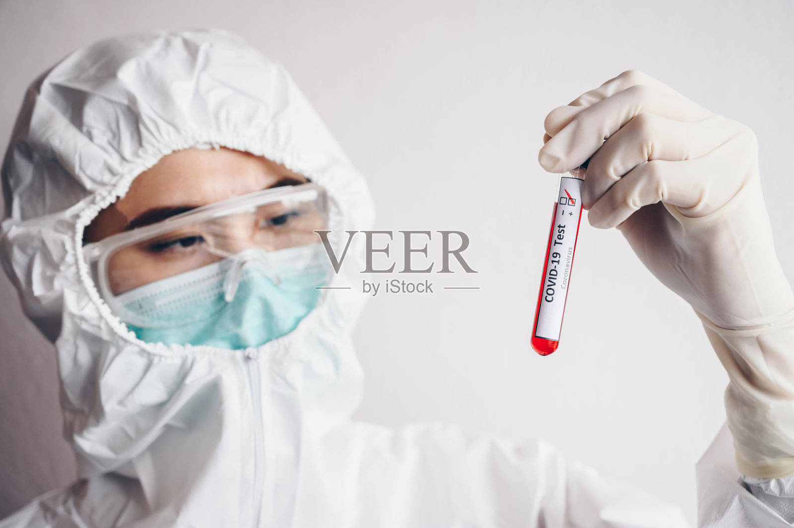 护士/医生穿着防护服，手持带有血液的样本试管进行新型冠状病毒分析。照片摄影图片