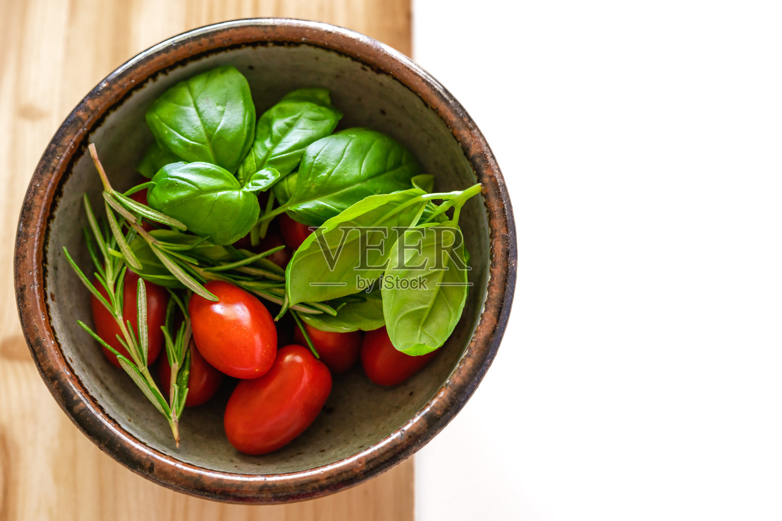 西红柿，迷迭香和罗勒放在碗里。新鲜蔬菜和香草近距离木质背景照片摄影图片