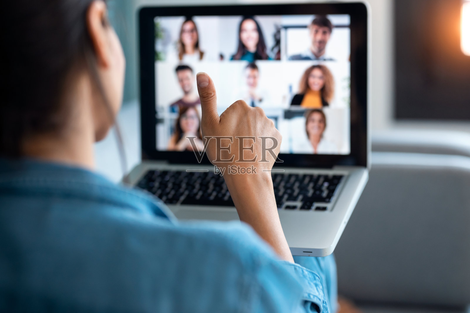 女商人坐在家里的沙发上进行视频通话，并在在线简报中对着笔记本电脑竖起大拇指。照片摄影图片
