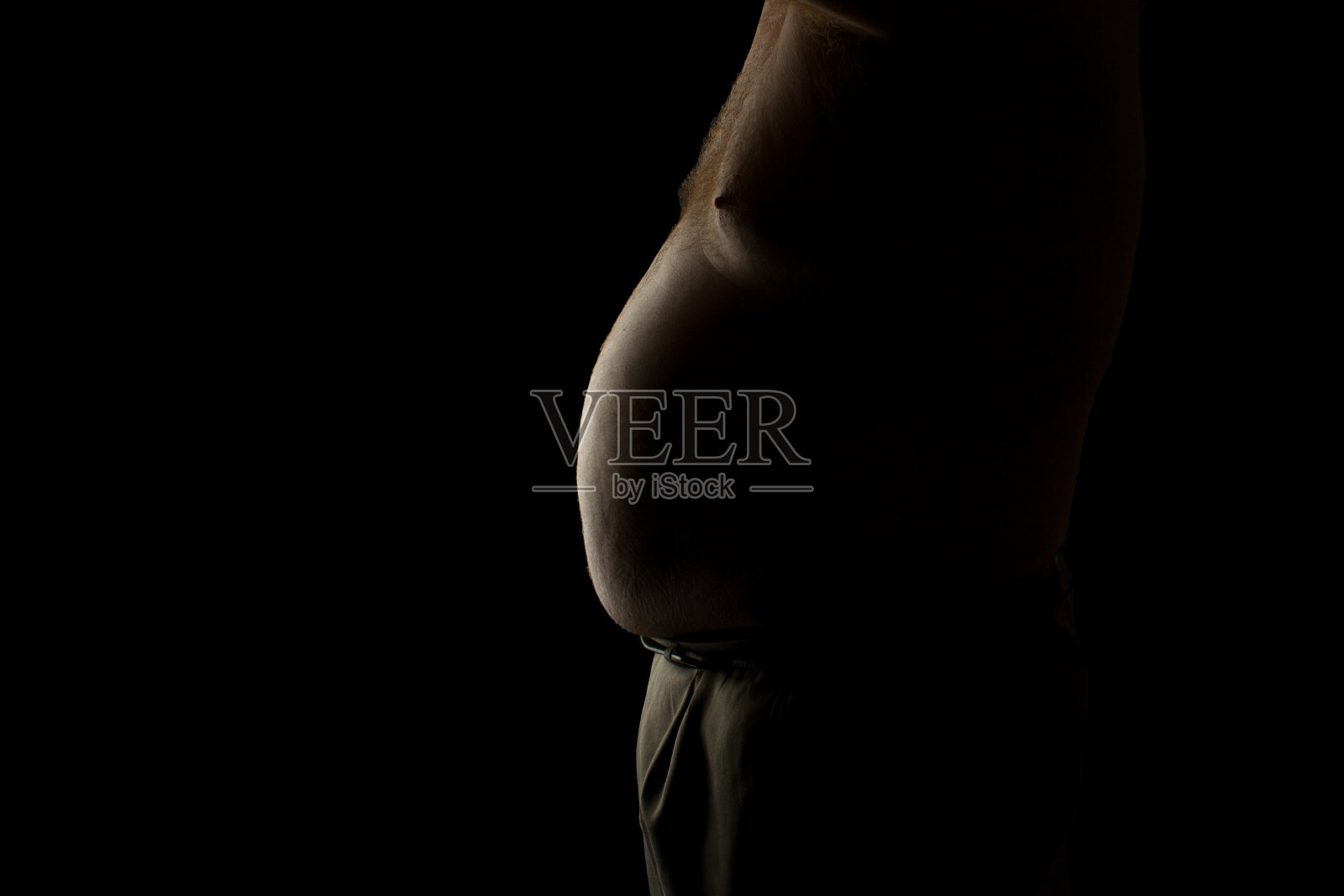 一个大肚子的胖子背光照亮了黑色的背景照片摄影图片