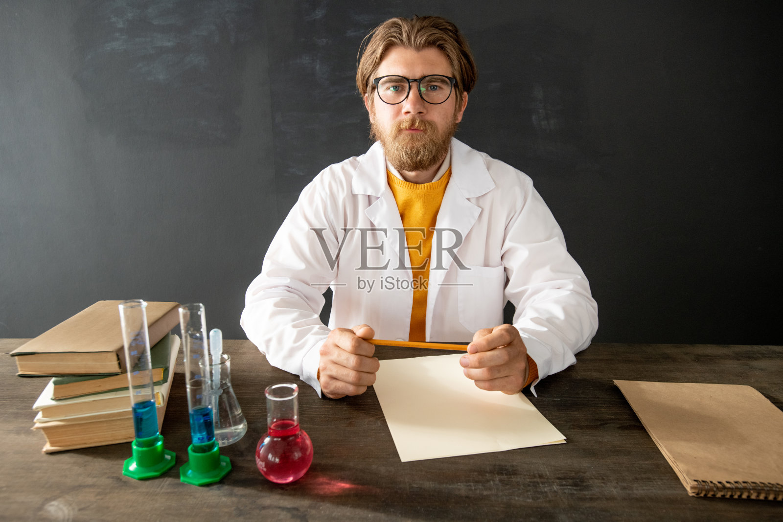 年轻自信的化学老师穿着白大褂看着他的在线听众照片摄影图片