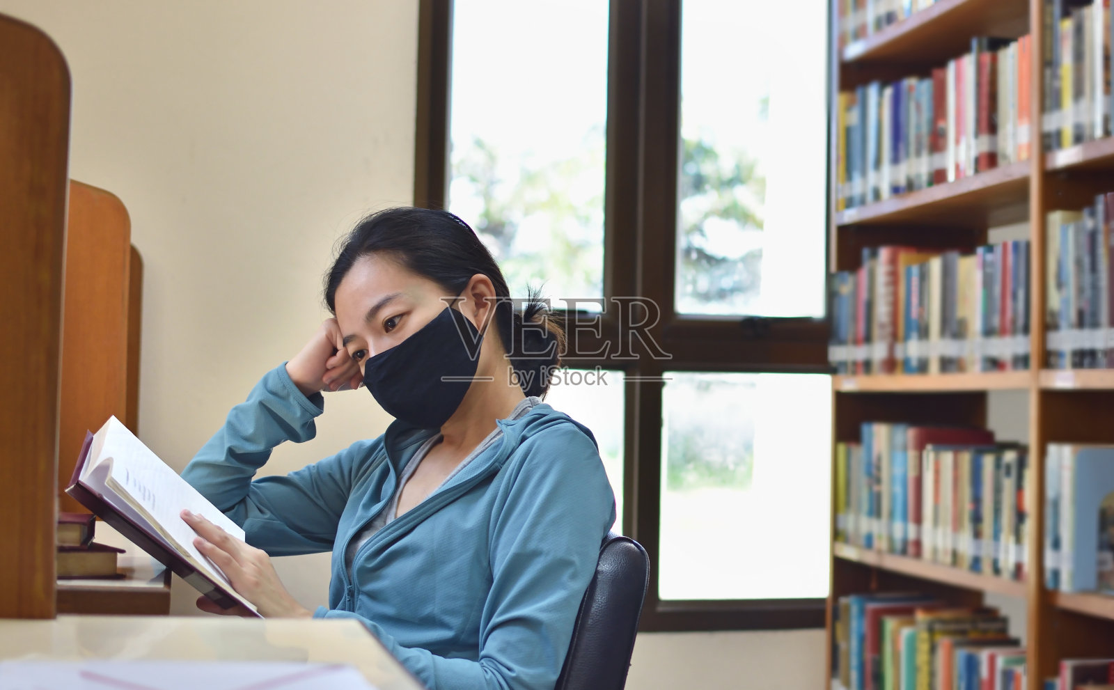 戴着防护面具在图书馆看书的女人照片摄影图片