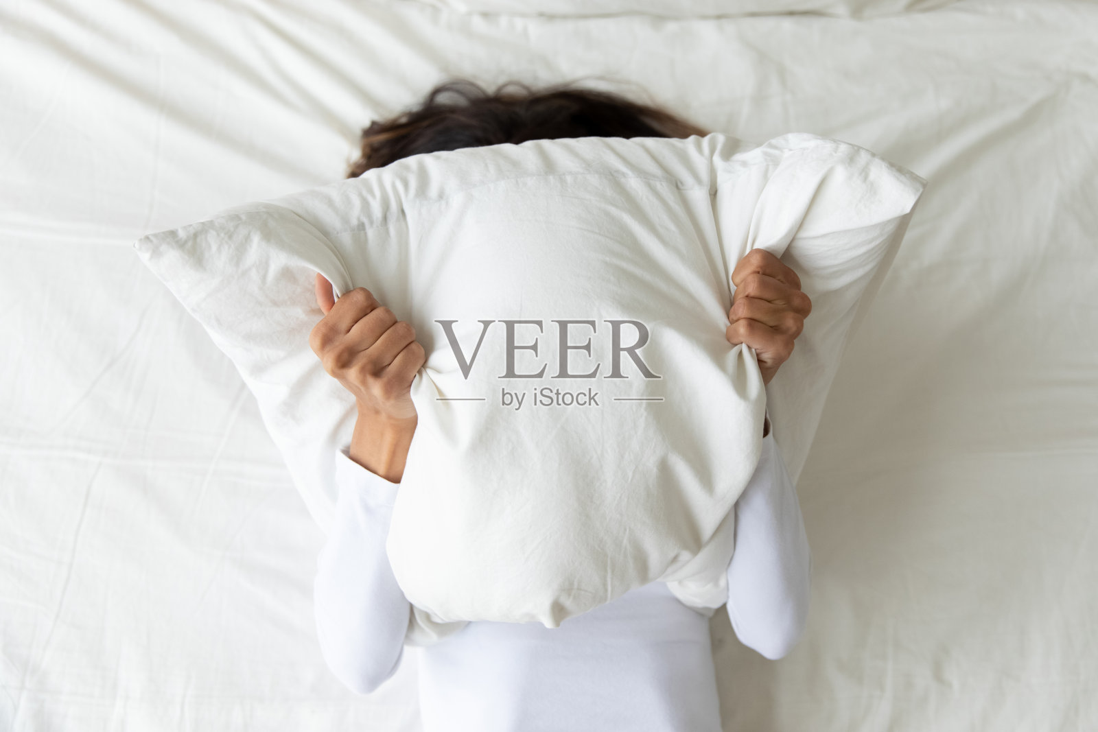 患有抑郁症的妇女用枕头遮住脸照片摄影图片