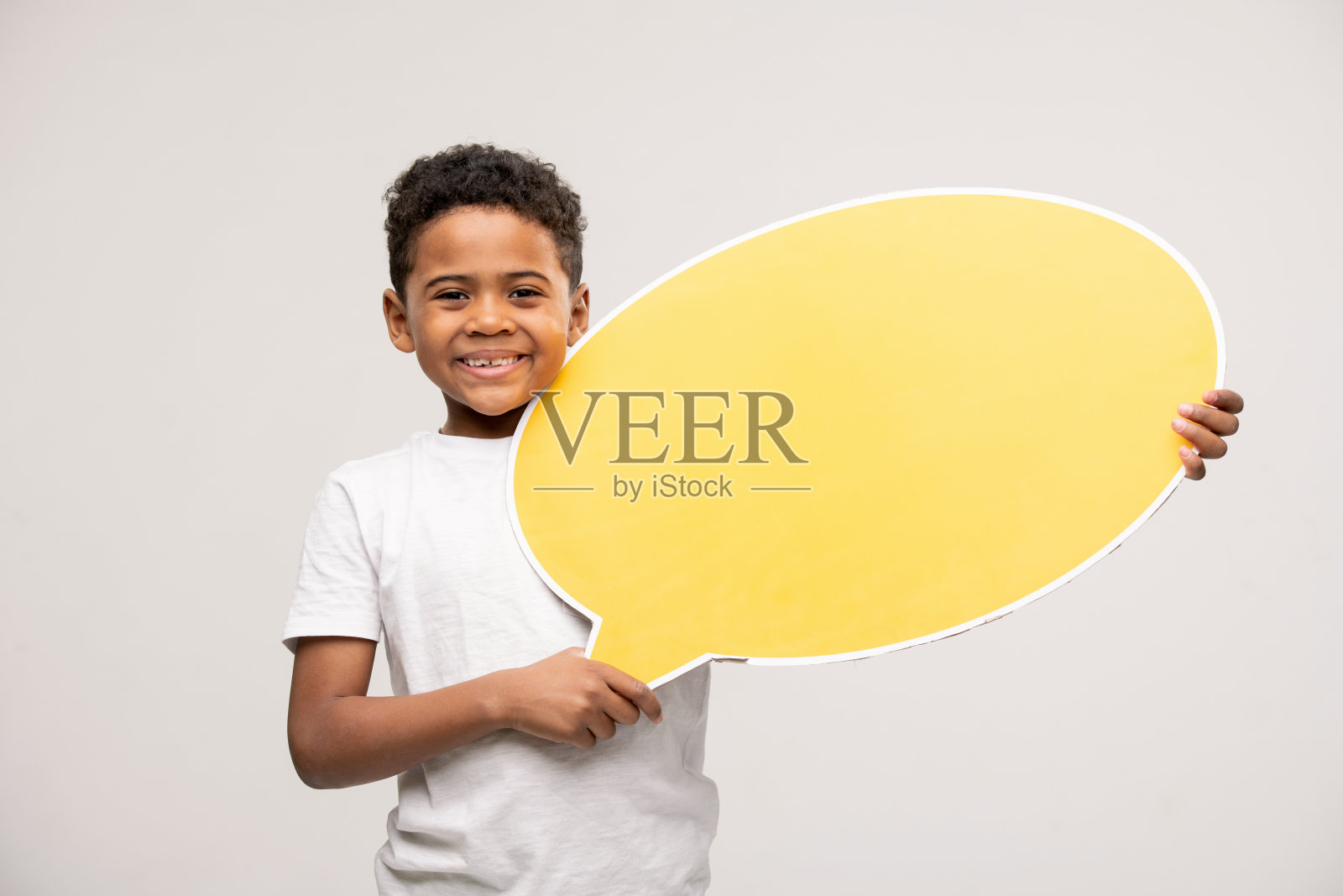 开朗的非洲裔小男孩，露出空白的黄色语音泡泡照片摄影图片