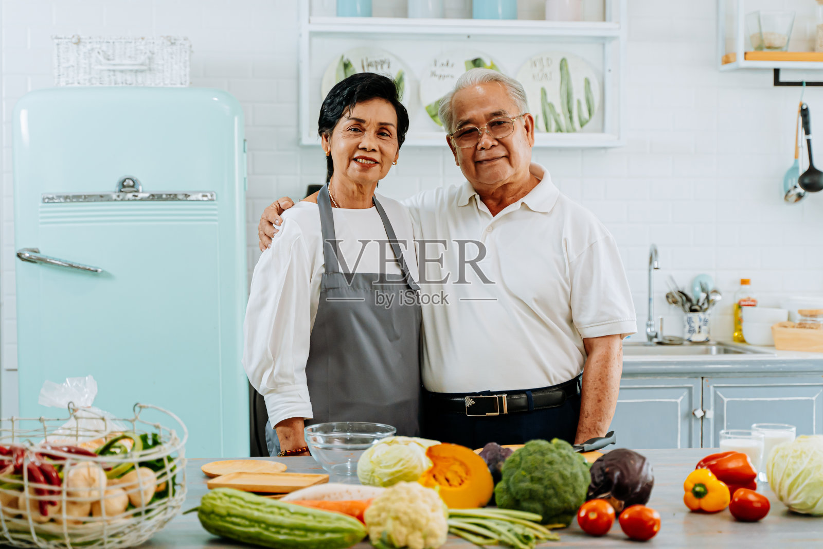 年长的亚洲夫妇在厨房做饭。70多岁的老人和女人一起在厨房柜台上准备食材照片摄影图片