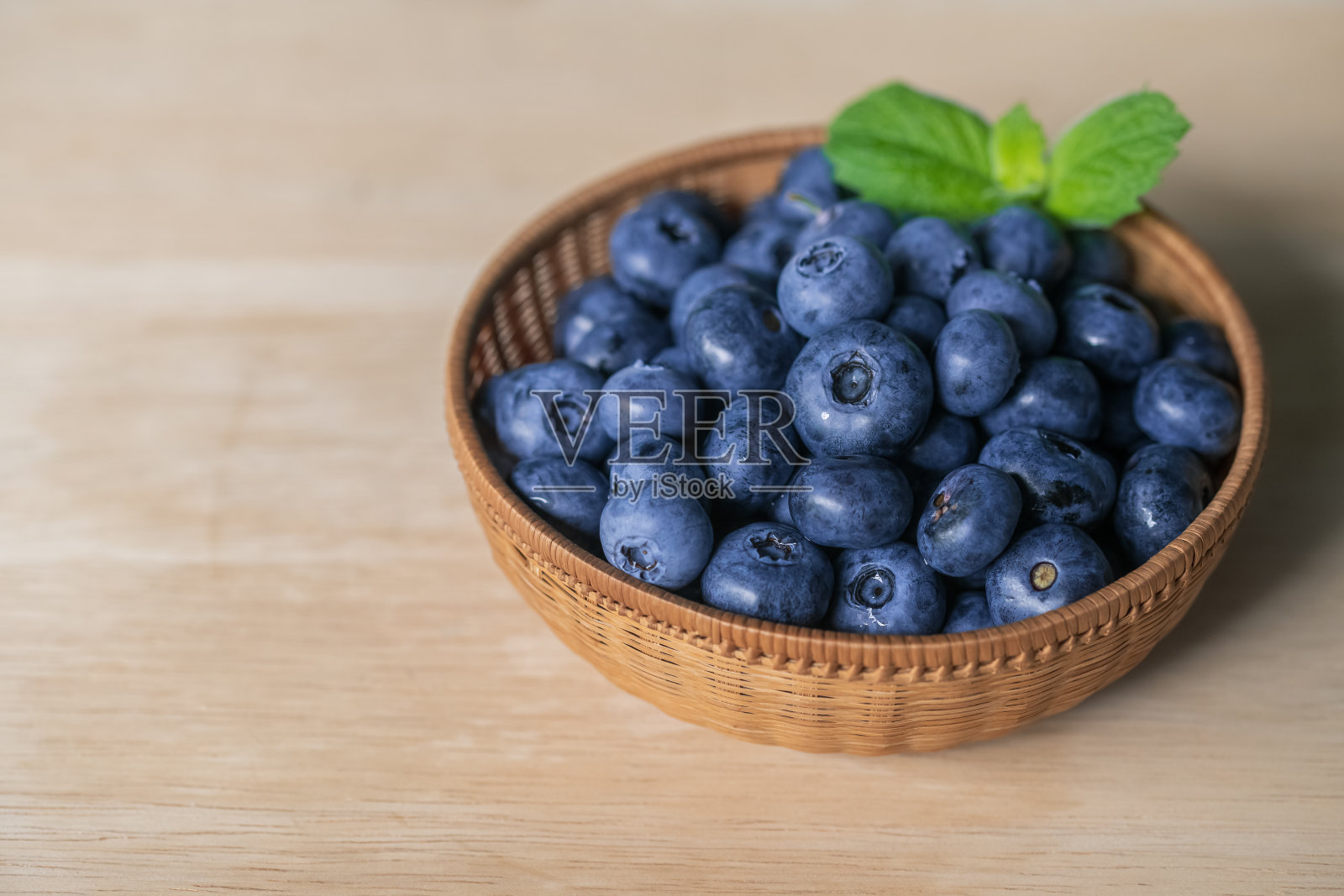 新鲜成熟的蓝莓在篮子里的木制背景。照片摄影图片