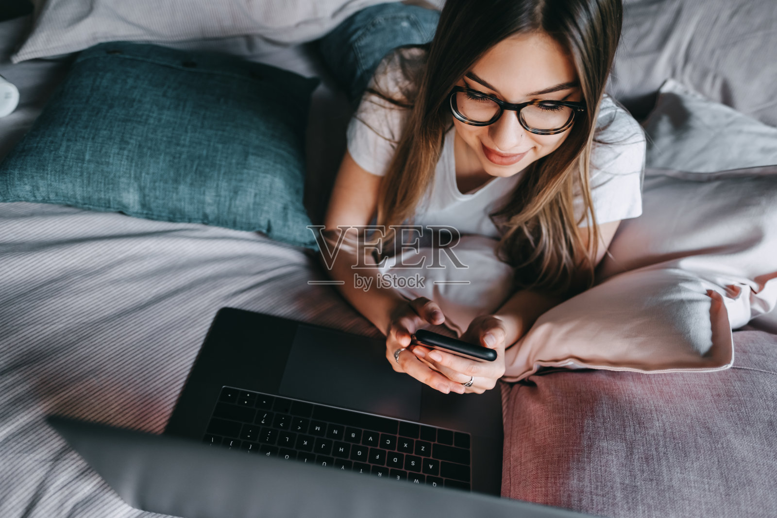美丽的年轻微笑的白人妇女休息在床上在家里使用笔记本电脑照片摄影图片
