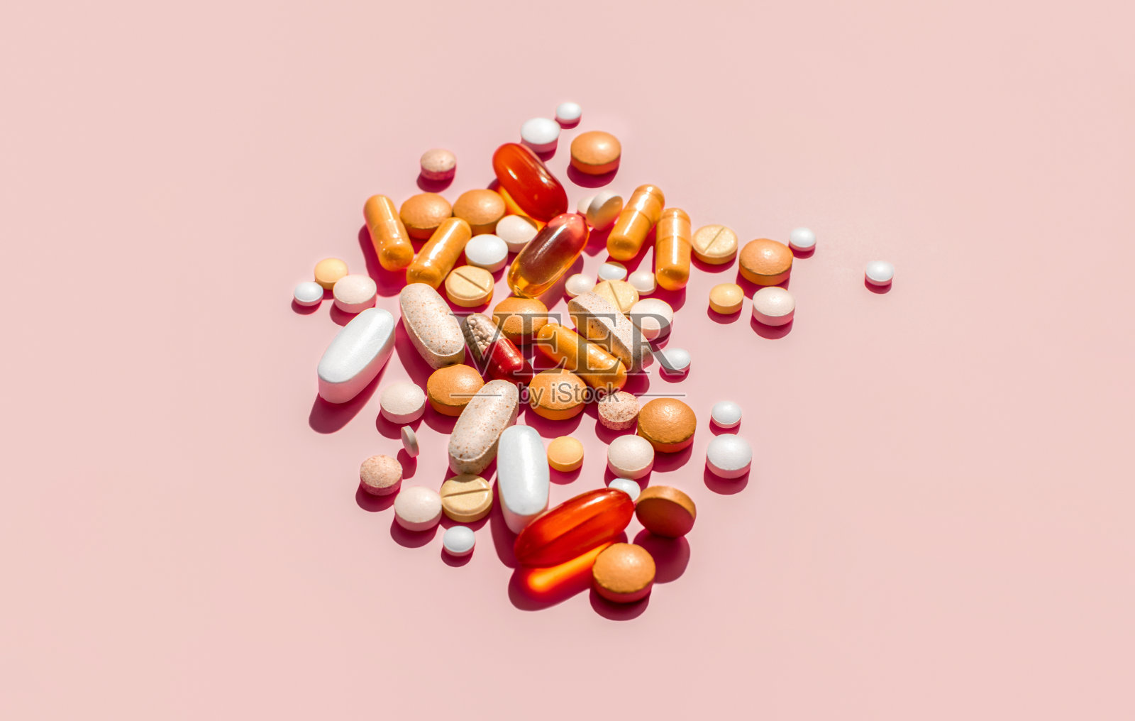 各种各样的药片躺在浅粉色的表面上照片摄影图片