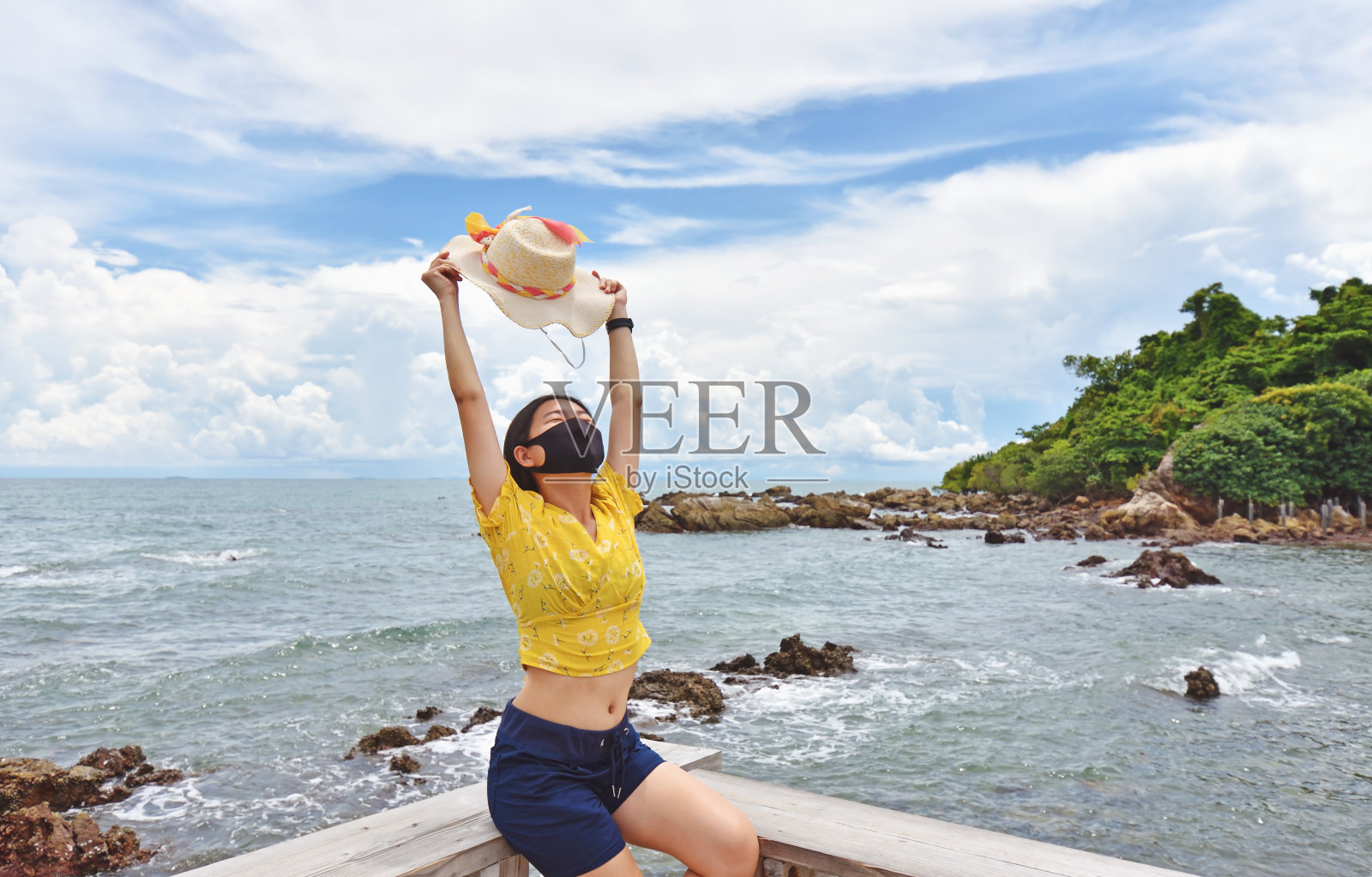 年轻女子戴着防护口罩在阳光下晒太阳。照片摄影图片