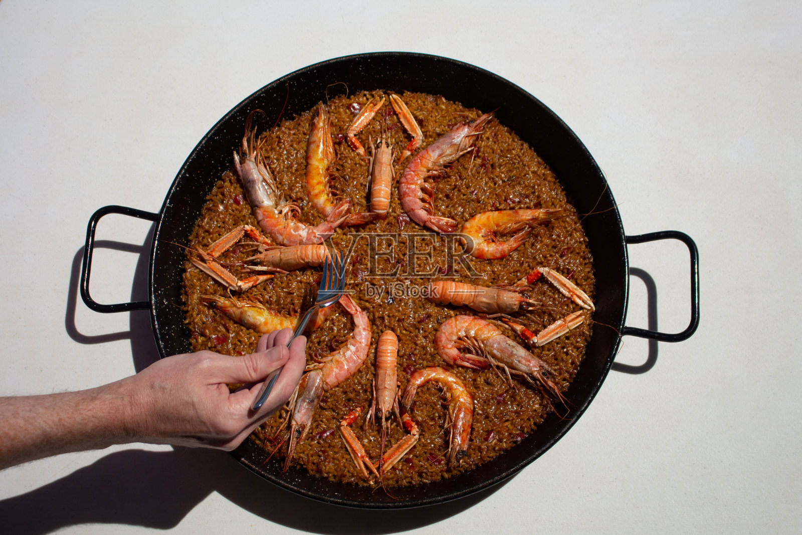 西班牙巴伦西亚，一名男子拿着叉子试图吃海鲜饭照片摄影图片