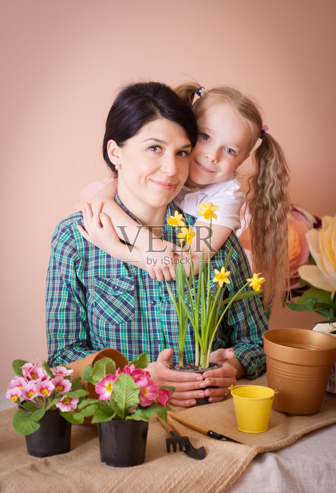 可爱的小女孩帮助妈妈照料植物。照片摄影图片