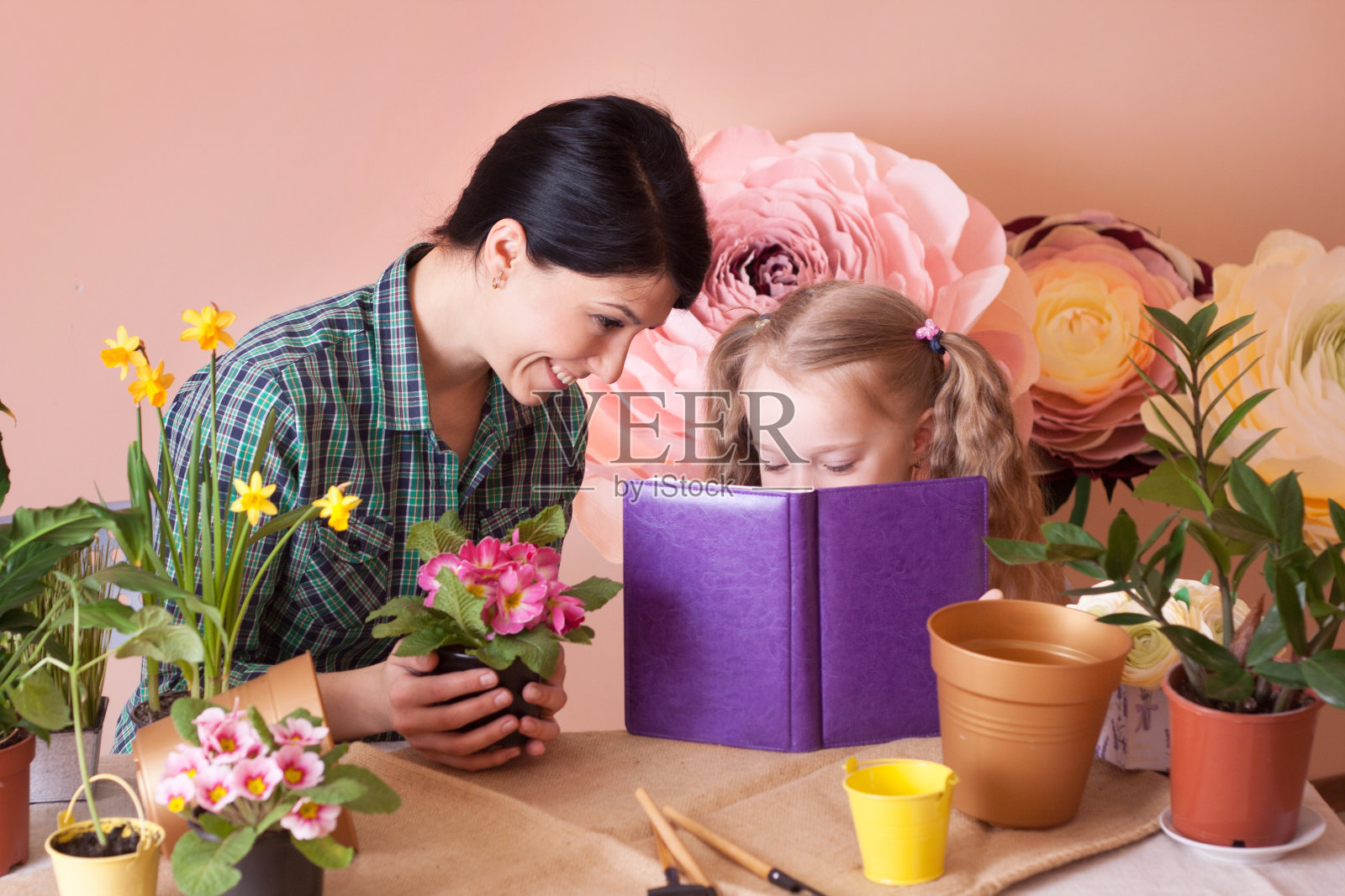 可爱的小女孩帮助妈妈照料植物。照片摄影图片