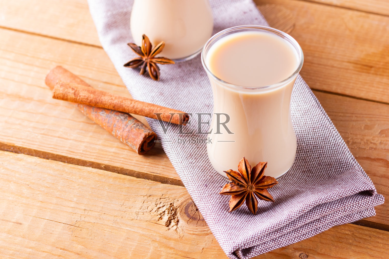 香草茶加牛奶和香料。自制的印度玛沙拉茶放在木板上。秋饮土耳其茶照片摄影图片