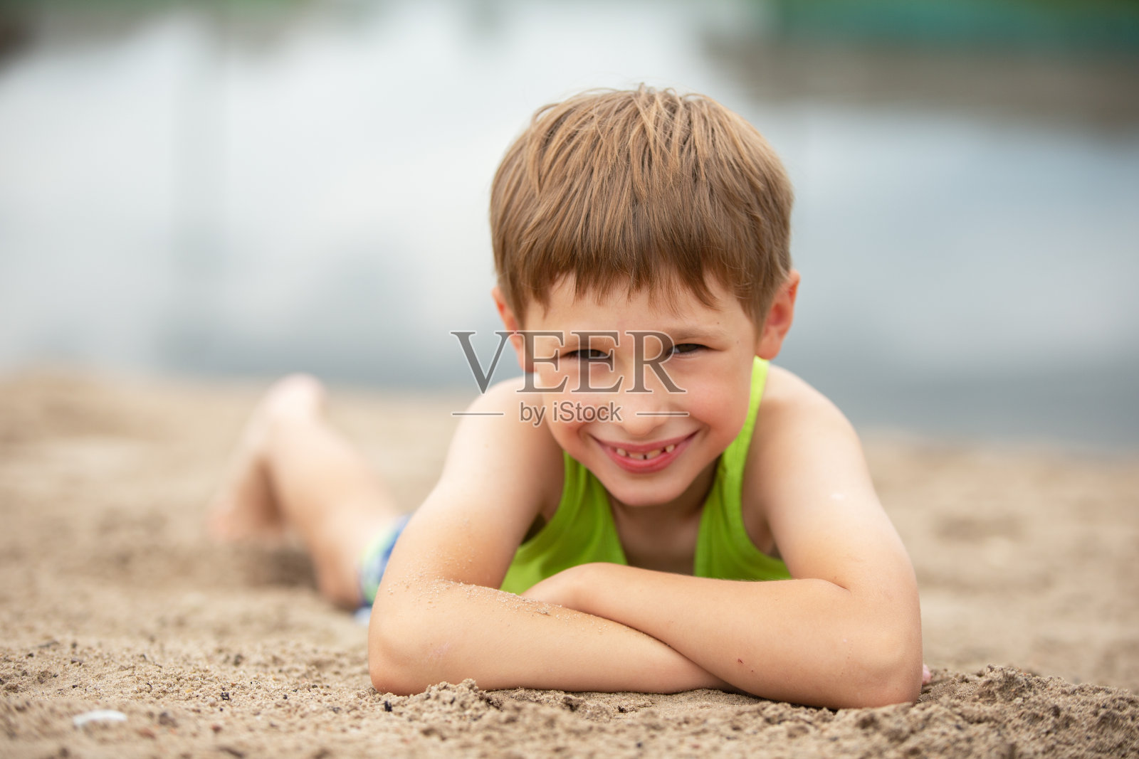 一个快乐的孩子在海边的沙滩上。一个穿着夏装的男孩在海滩上的肖像。照片摄影图片