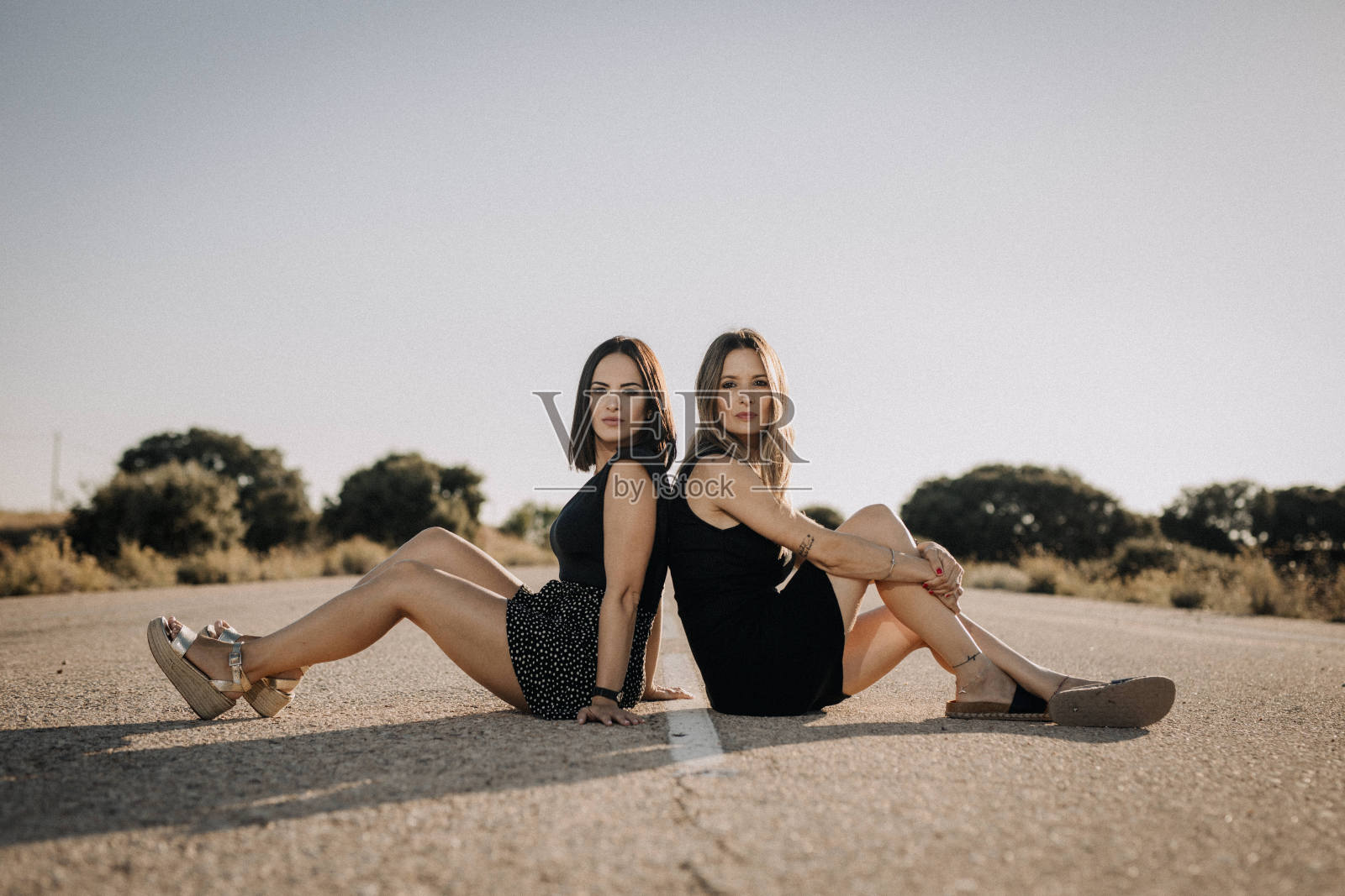 两个漂亮女人坐在路上照片摄影图片