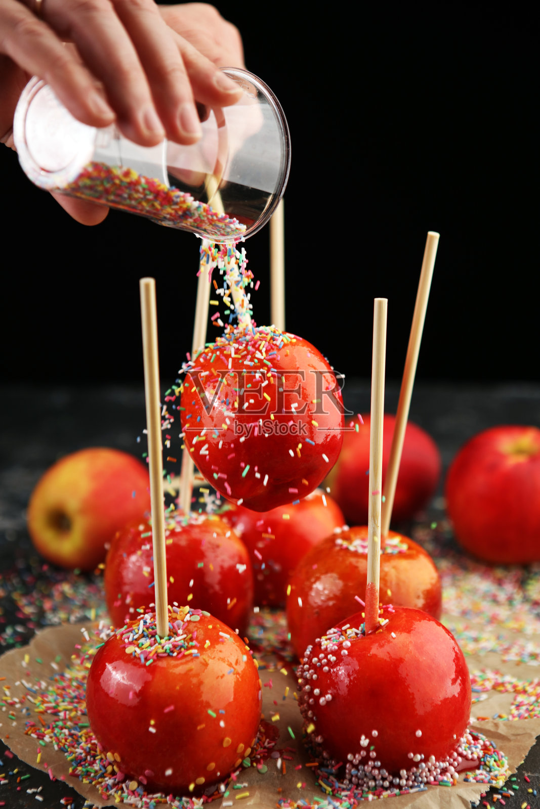 在农贸市场或乡村集市上为孩子们出售的甜的红色糖霜太妃糖苹果棒。照片摄影图片
