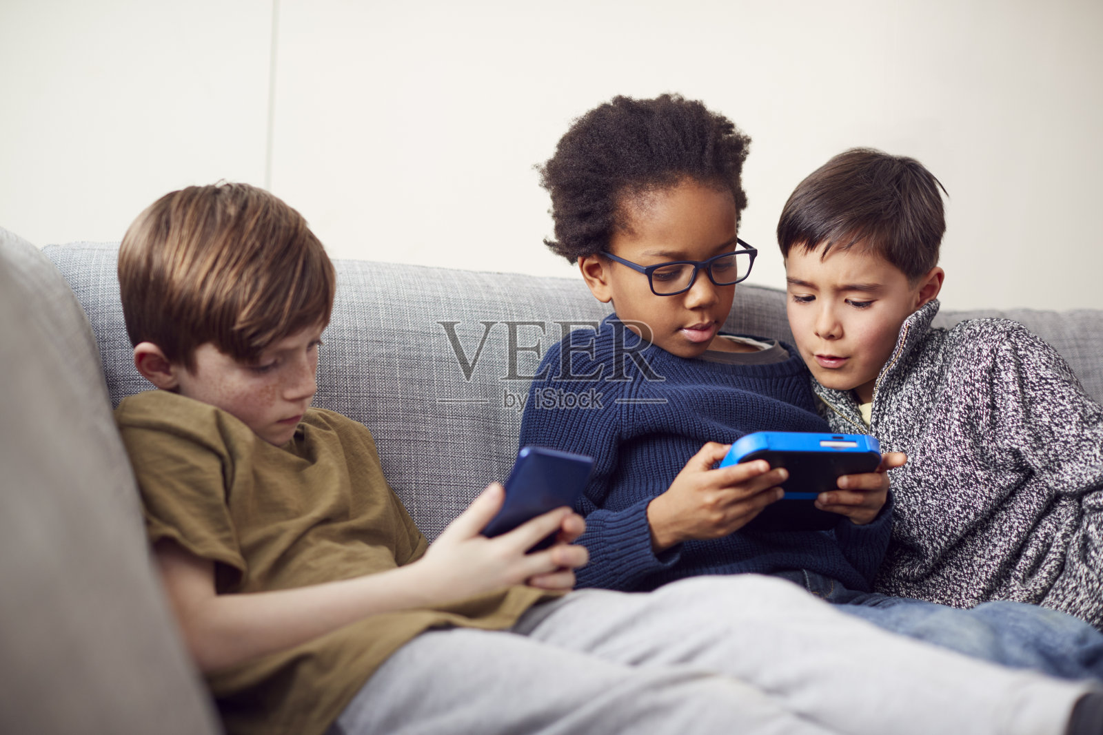 一群年轻男孩在家里用手持设备一起玩游戏照片摄影图片