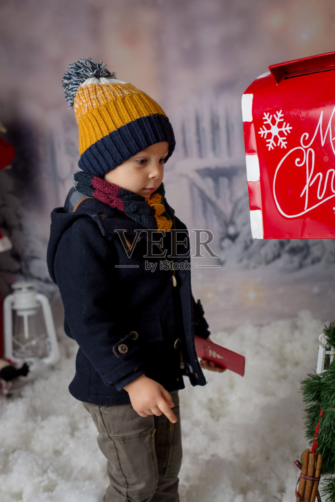 蹒跚学步的孩子，男孩穿着时髦的衣服，拿着小圣诞树照片摄影图片