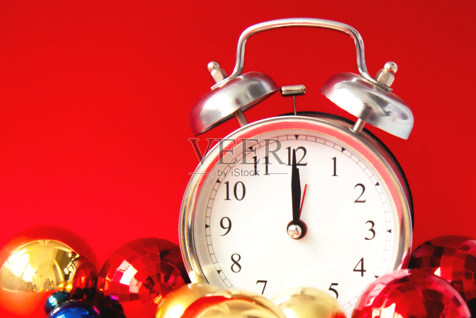 美丽的银色古董闹钟和红色，蓝色和金色的圣诞球在明亮的红色背景照片摄影图片