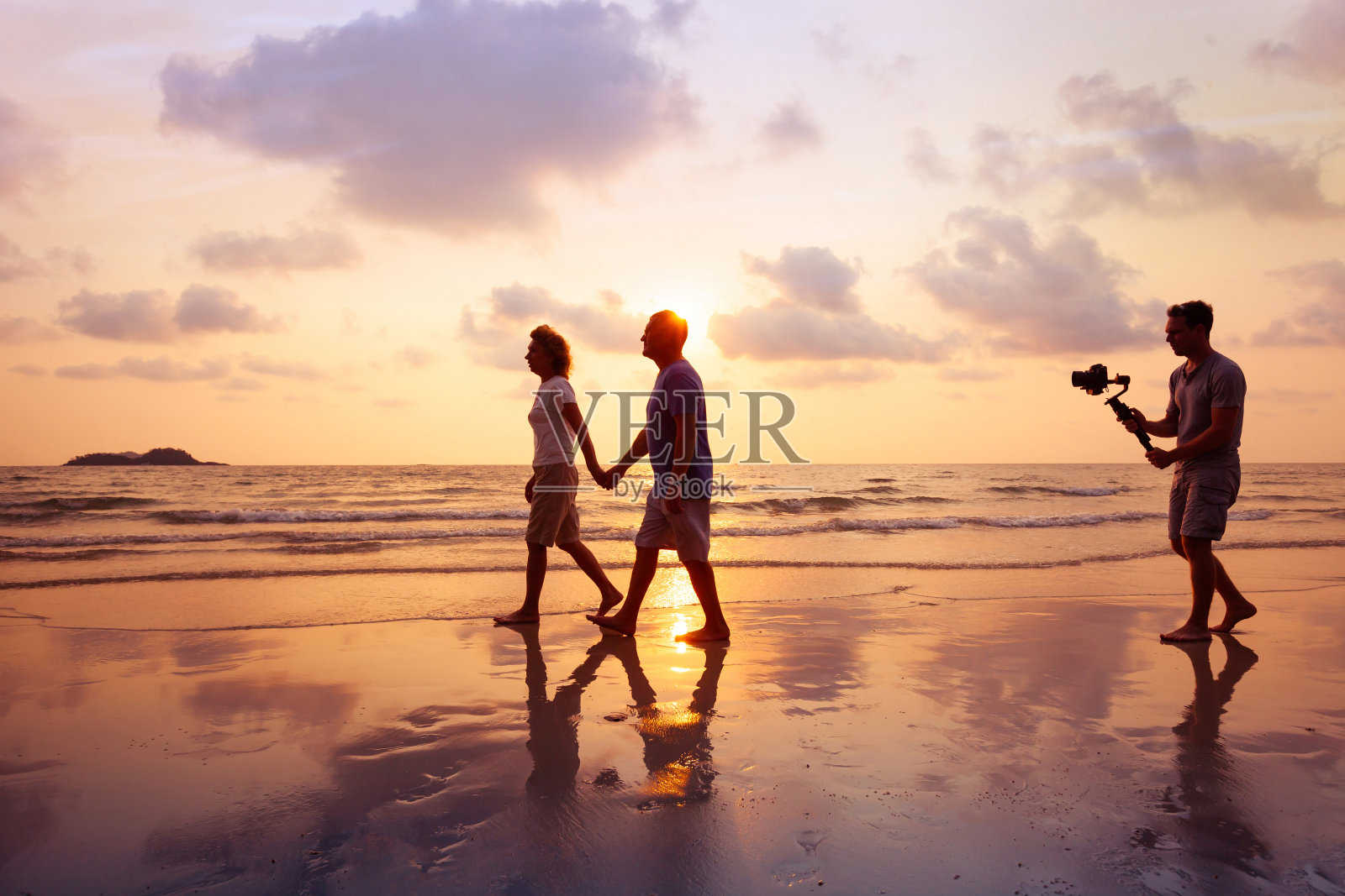 电影制作人，专业摄像师，夕阳西下，在海滩上用照相机稳定器拍摄夫妻视频照片摄影图片
