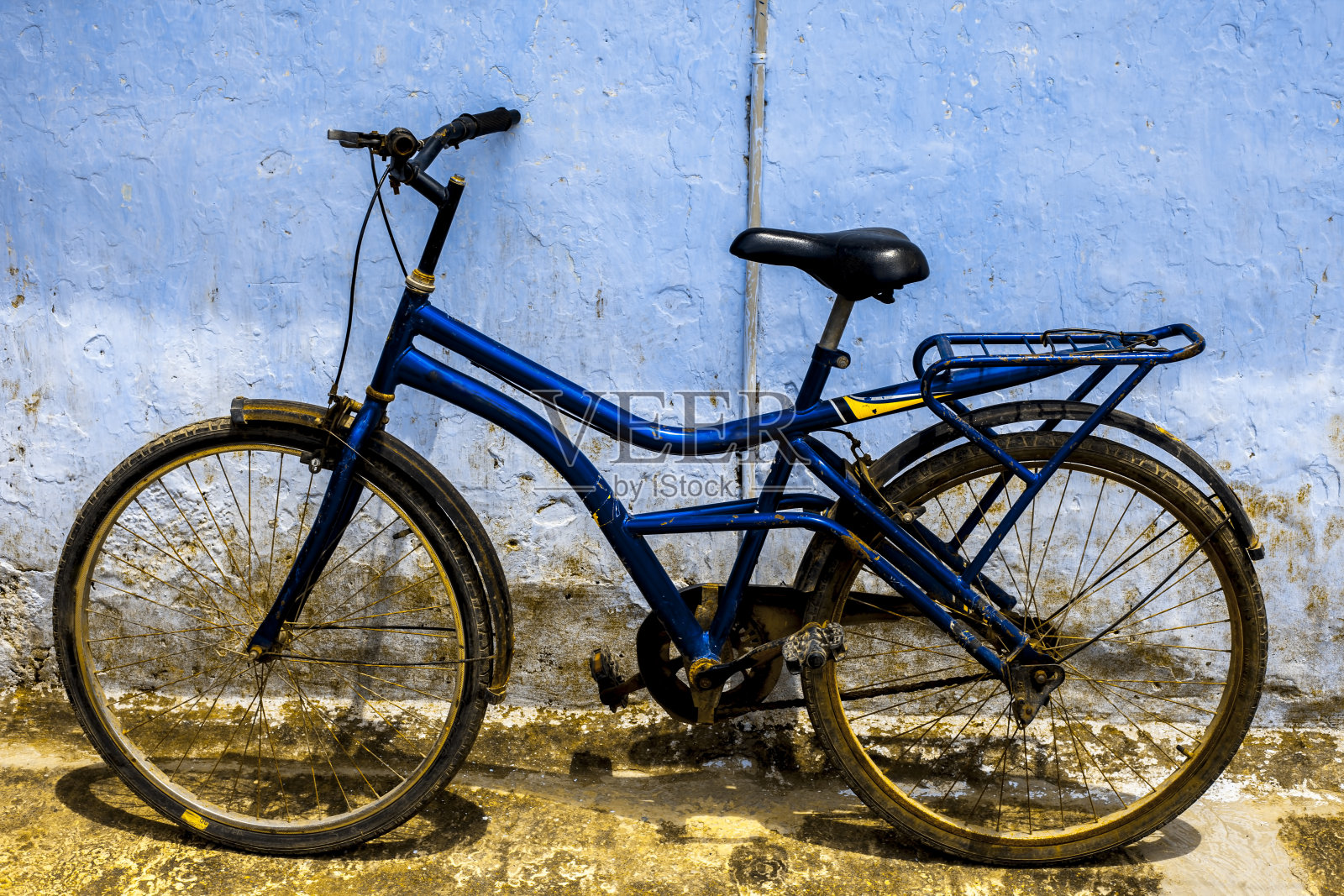 蓝色的自行车孤立地靠在蓝色的墙上。照片摄影图片