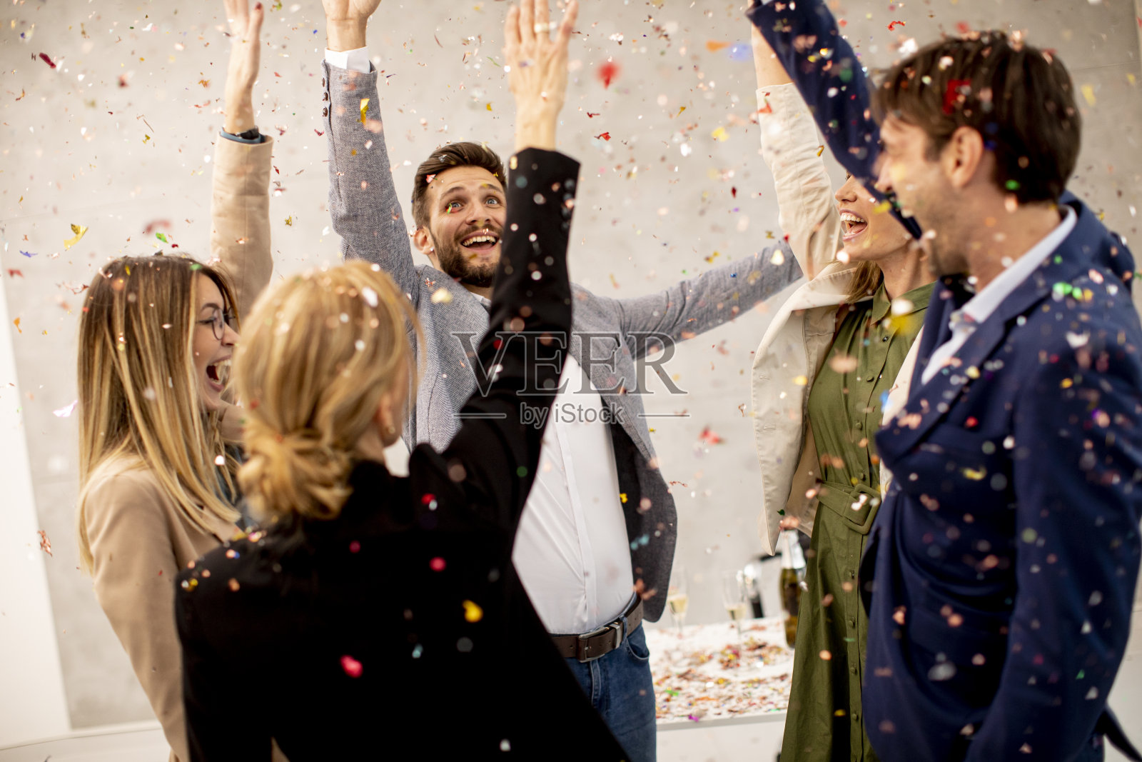 一群商业人士庆祝和祝酒，五彩纸屑散落在办公室里照片摄影图片