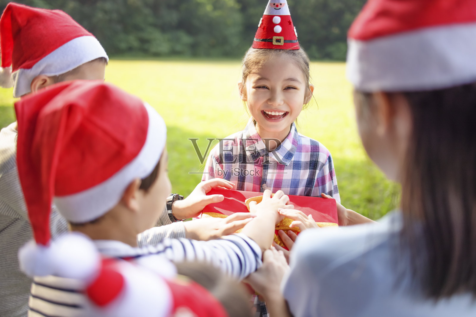 快乐的孩子戴着圣诞老人的红帽，拿着圣诞礼物照片摄影图片