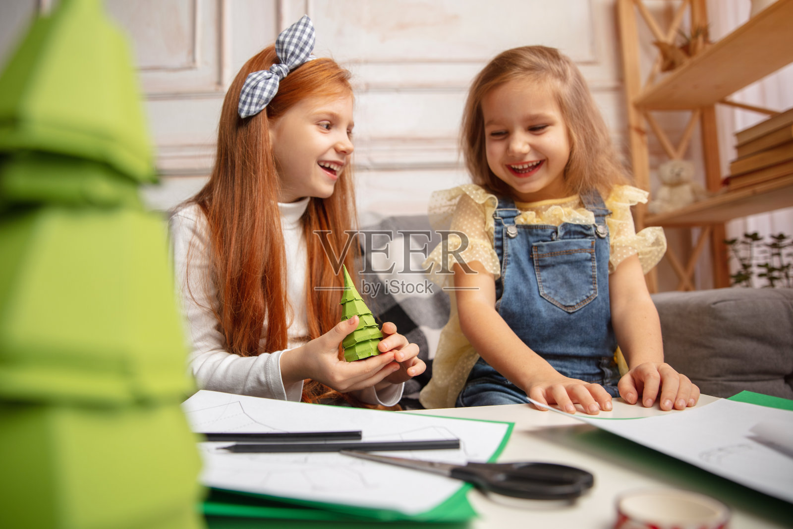 两个小孩，女孩一起在创造力的房子。快乐的孩子们为游戏或庆祝新年自制玩具照片摄影图片