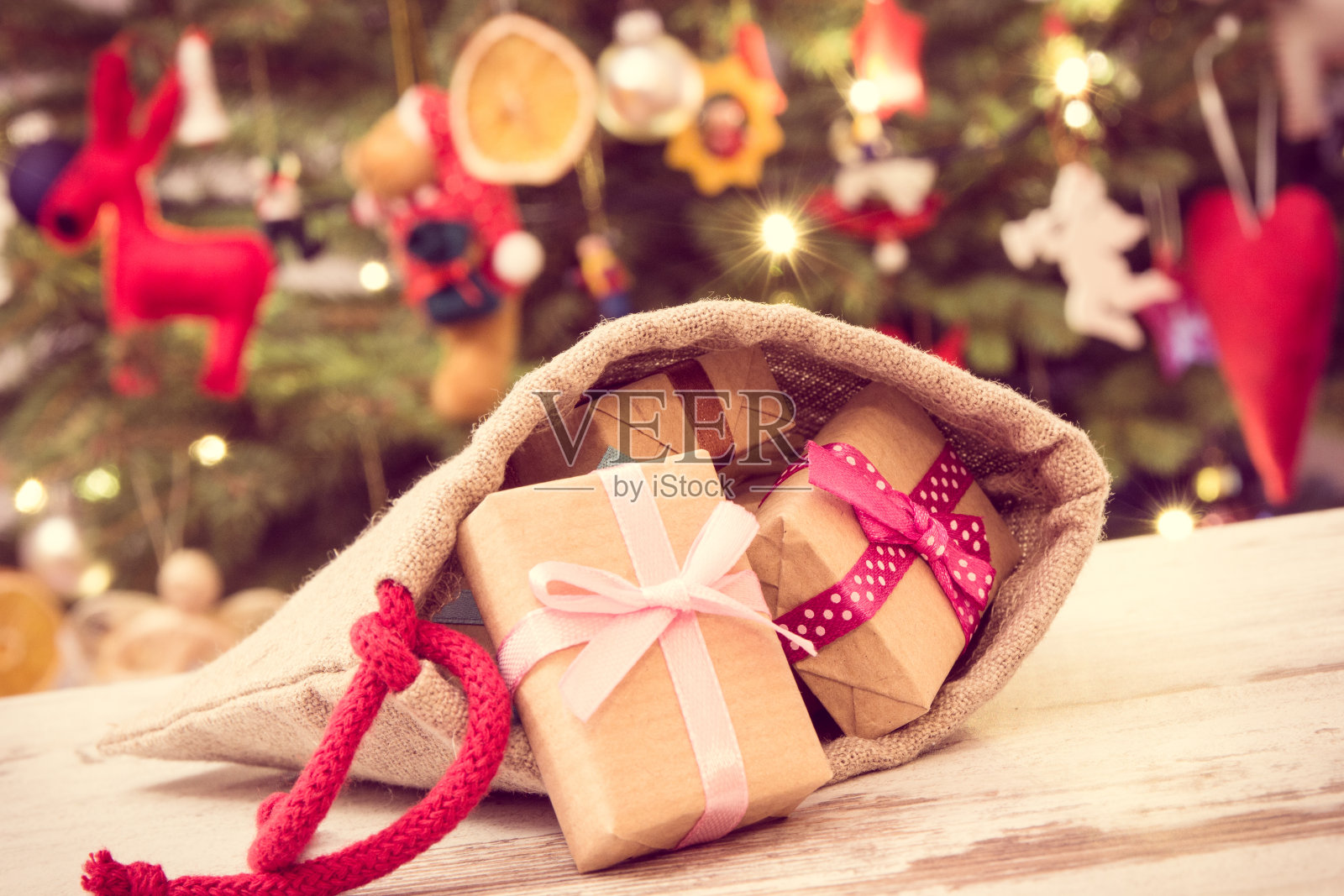 复古照片，包装礼物与丝带在黄麻袋为圣诞节和圣诞树装饰，圣诞时间的概念照片摄影图片