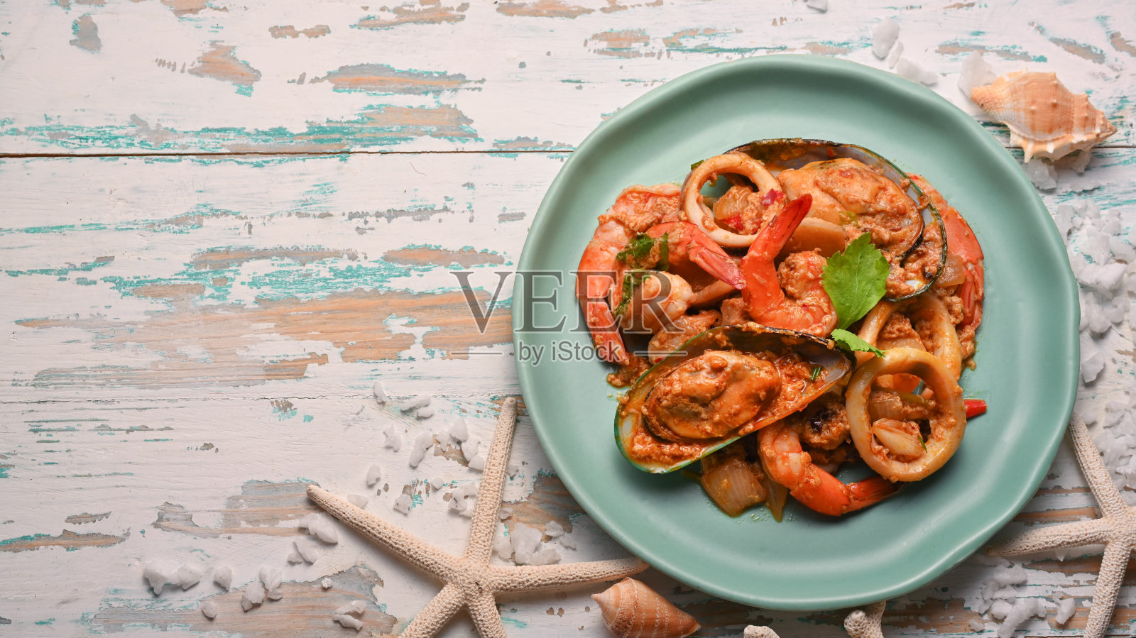 泰式料理、海鲜炒咖喱粉放在绿色陶瓷板上的木桌上照片摄影图片