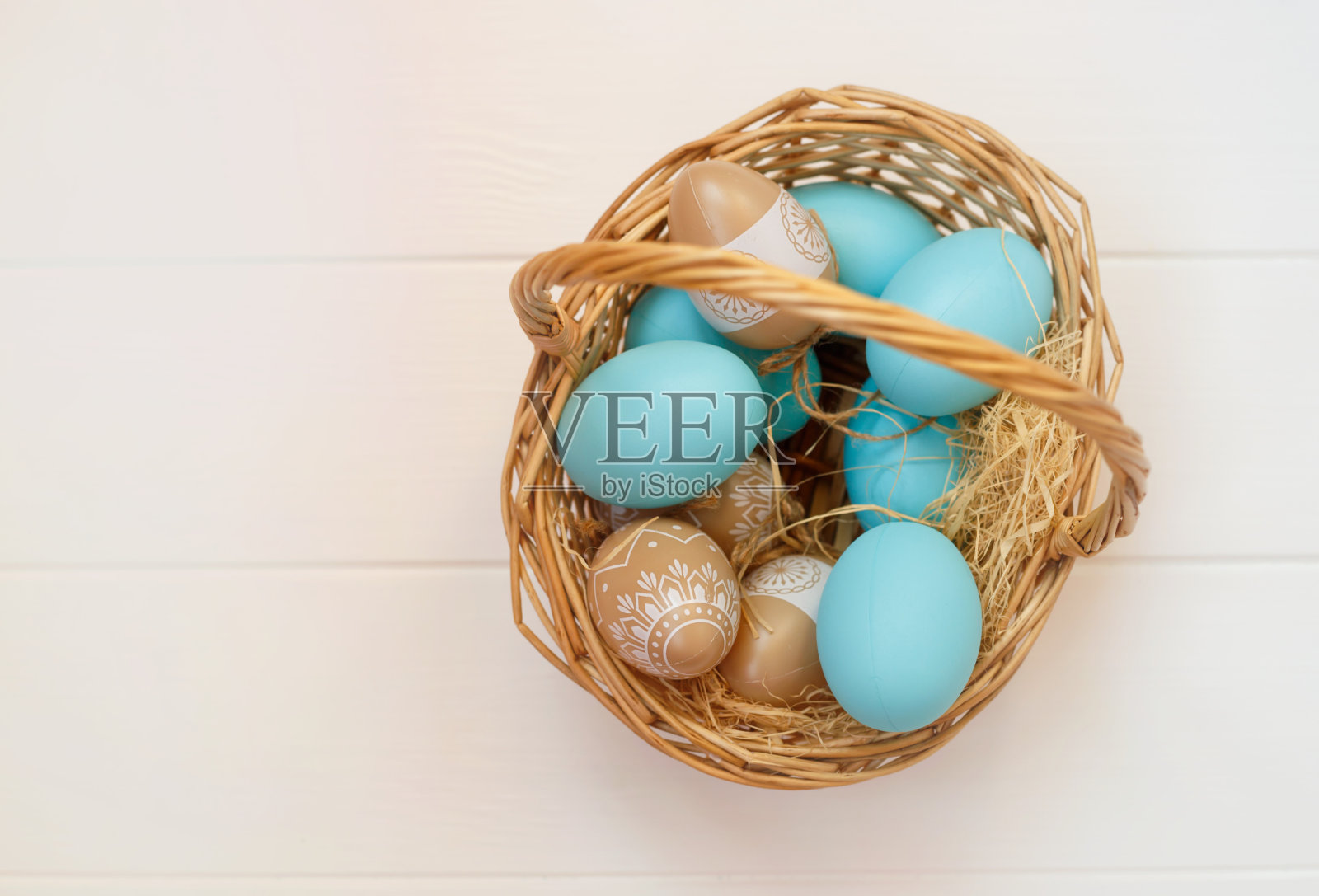 柳条篮子与蓝色和米黄色的鸡蛋在木制背景照片摄影图片