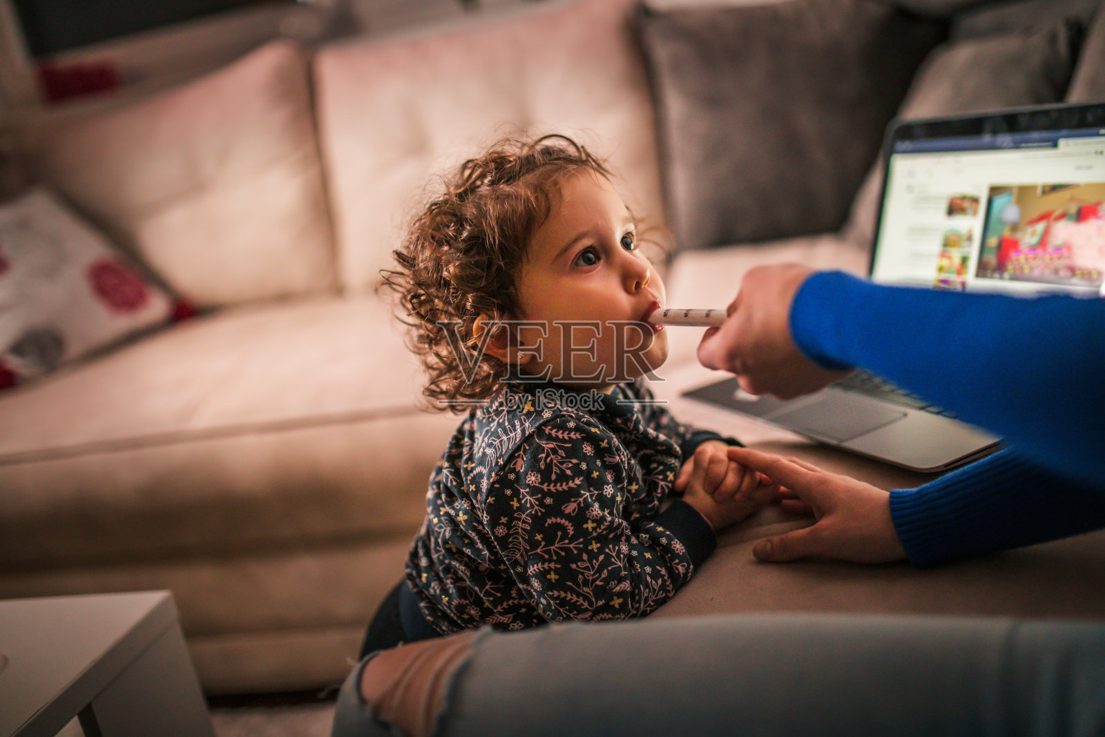 一家人和小女儿坐在家里的沙发上看笔记本电脑照片摄影图片