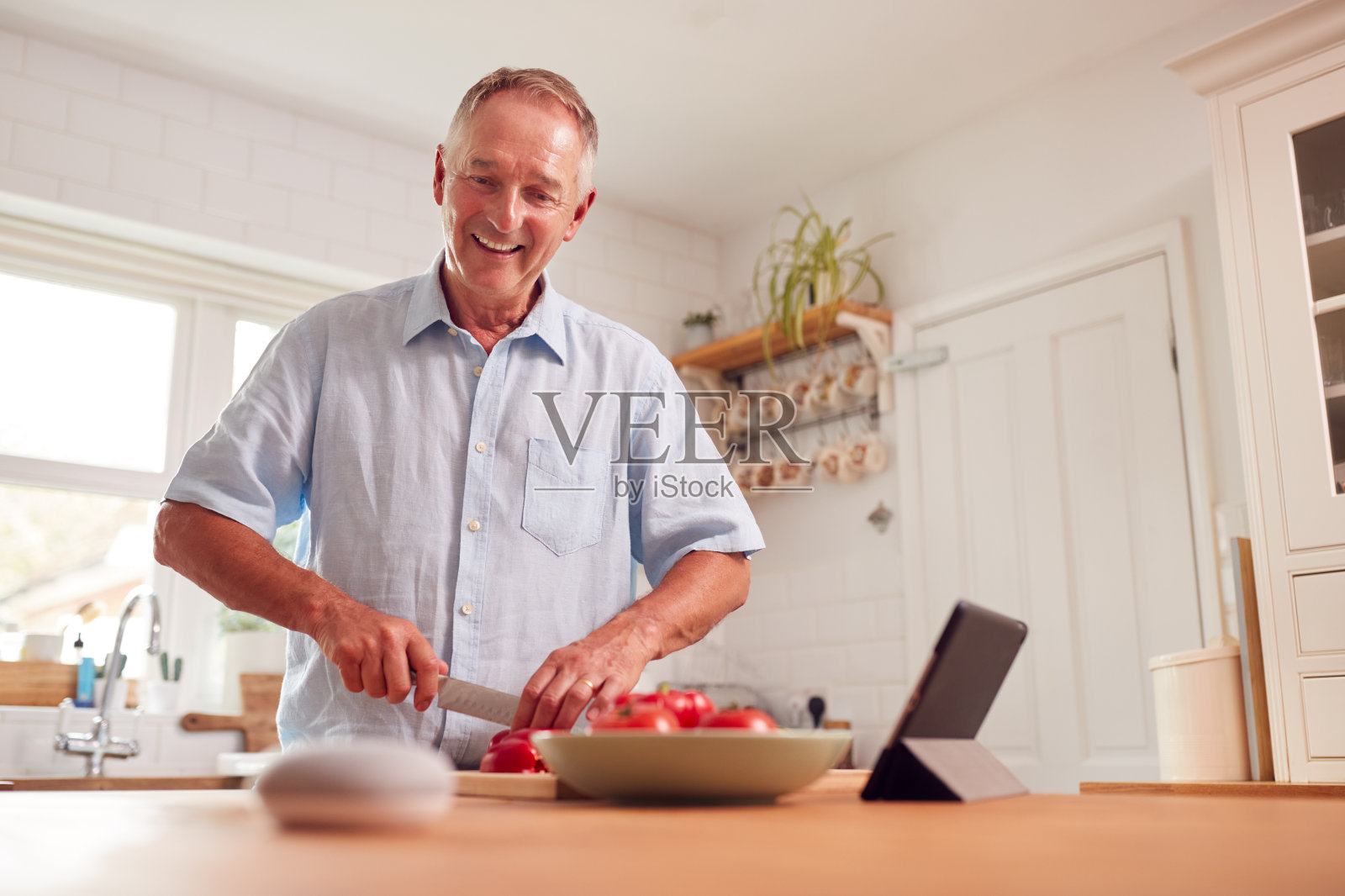 退休男子在厨房做饭，问智能扬声器前景问题照片摄影图片