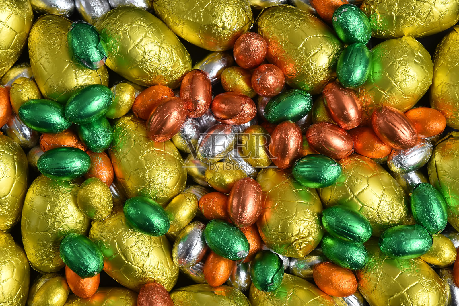 大、小黄、金、橙、绿、银等春季颜色的巧克力复活节彩蛋，以黑色为背景。照片摄影图片