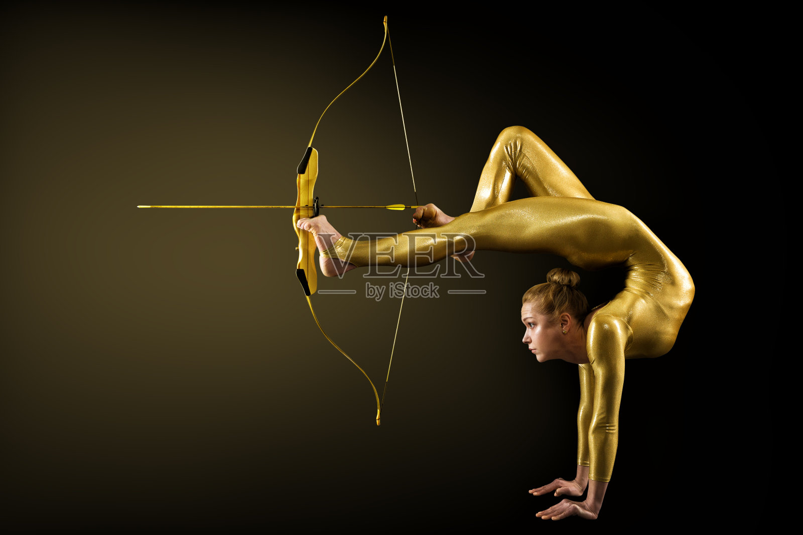 用金弓和箭的腿射箭。柔韧体操手倒立瞄准目标。目标实现的概念照片摄影图片