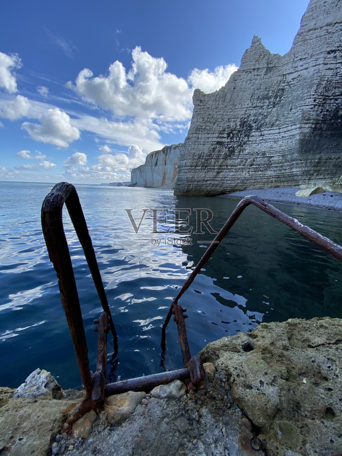 在法国海岸埃特尔塔的石灰岩悬崖上，梯子在海上下降照片摄影图片