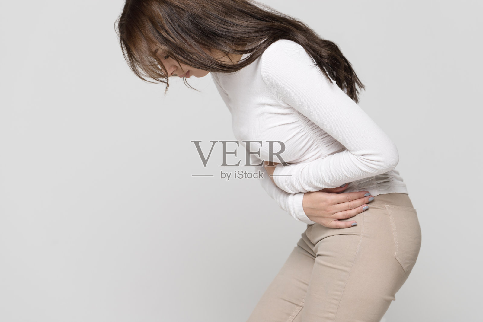 女性患有胃痛，感到腹痛或痉挛时，侧视。月经期照片摄影图片