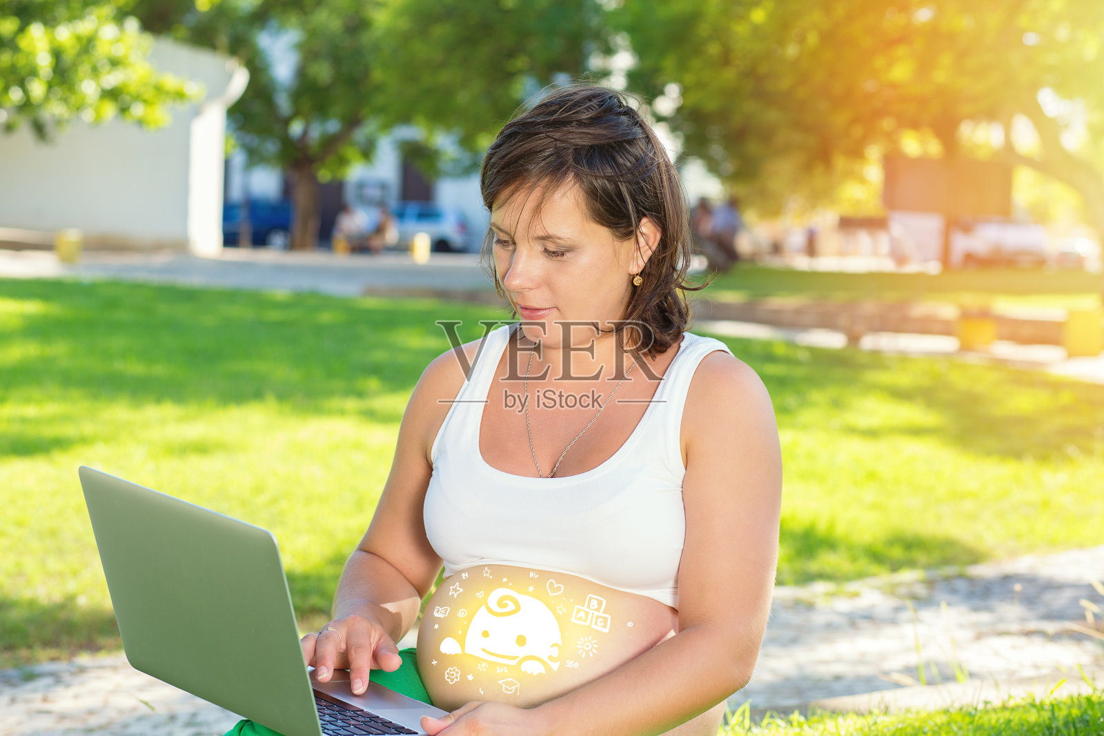 快乐的孕妇在户外用笔记本电脑工作照片摄影图片