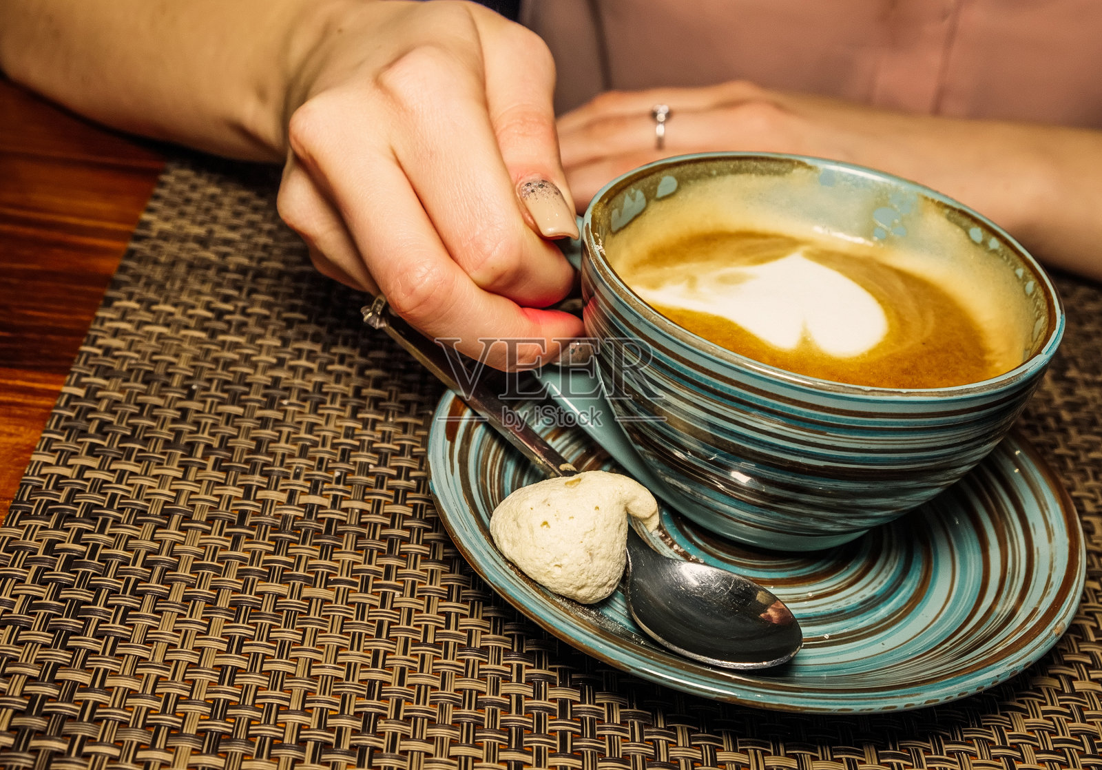 咖啡桌上放着一杯咖啡，女孩手里举着一杯牛奶咖啡。一张描绘舒适放松的咖啡休息时间的照片照片摄影图片