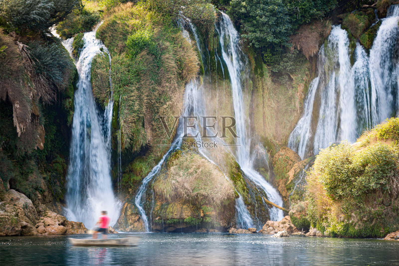 Kravice瀑布，波斯尼亚和黑塞哥维那，欧洲。夏季旅行。瀑布脚下的游船。照片摄影图片