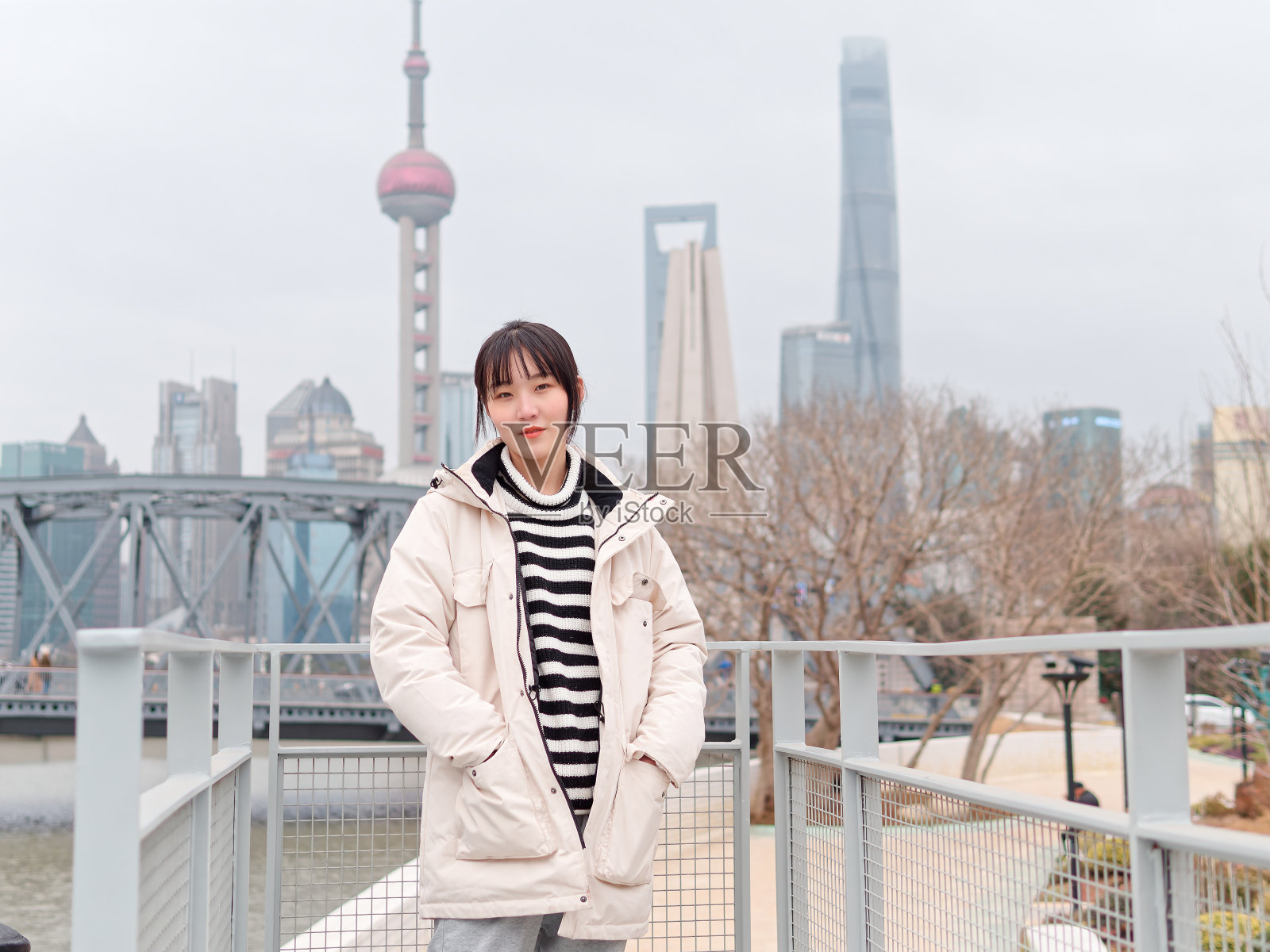冬日里以上海地标为背景的中国年轻女子的肖像。照片摄影图片
