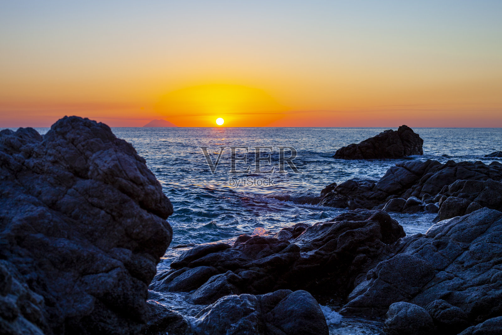 岩石海岸上的日落。照片摄影图片