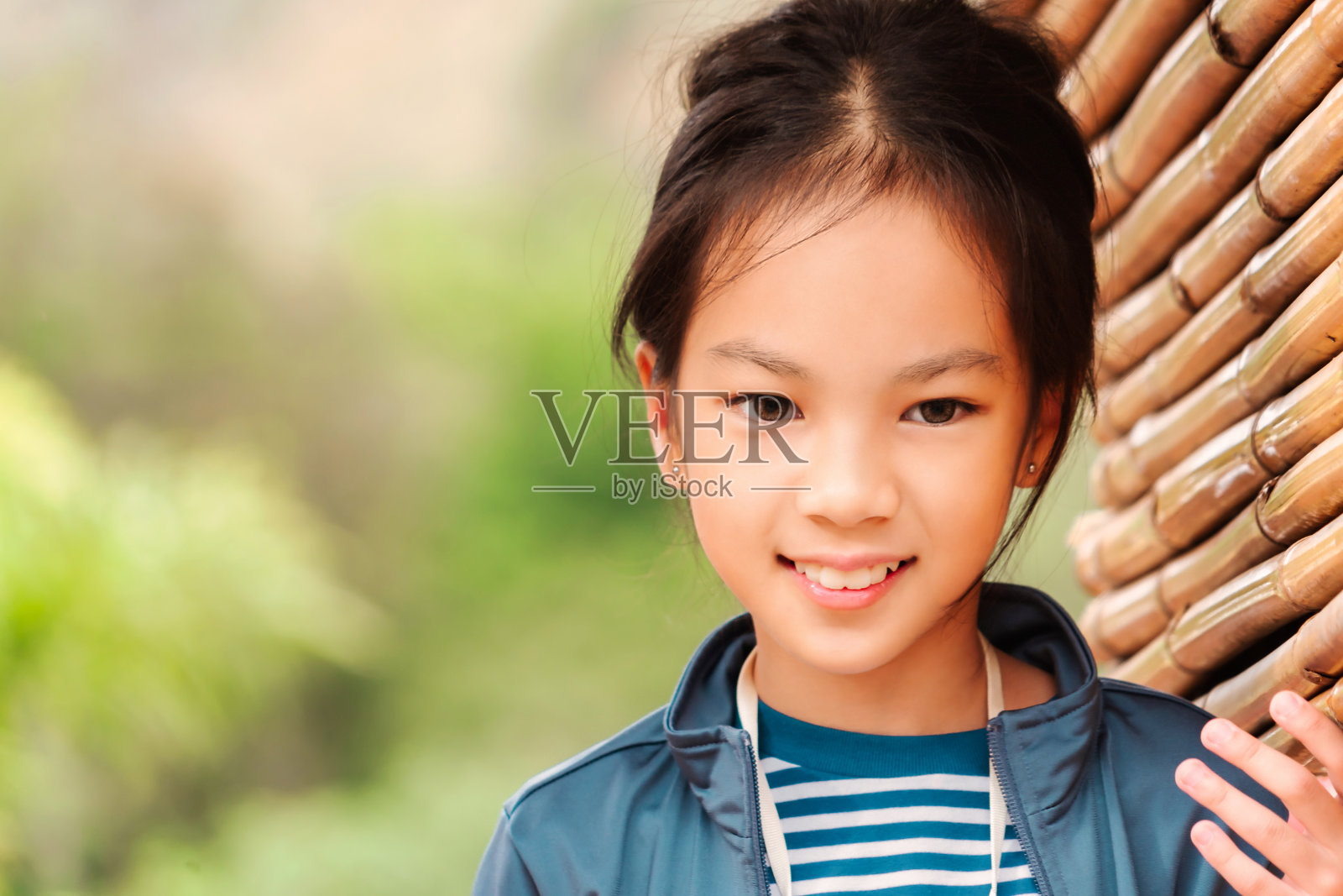 快乐的亚洲小女孩看着镜头微笑，在公园的竹木操场上玩耍照片摄影图片