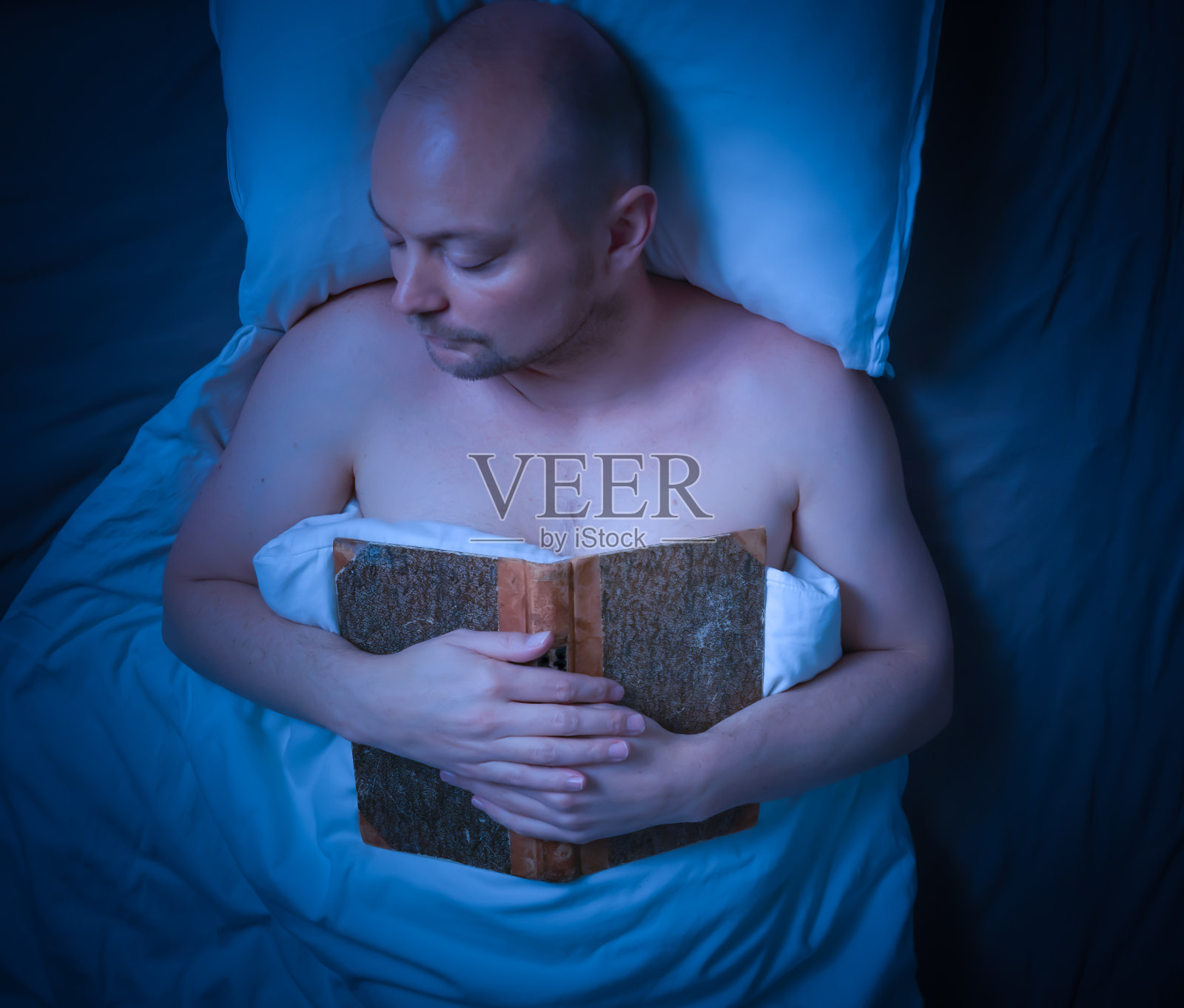 看完一本书后，男人睡在床上。照片摄影图片