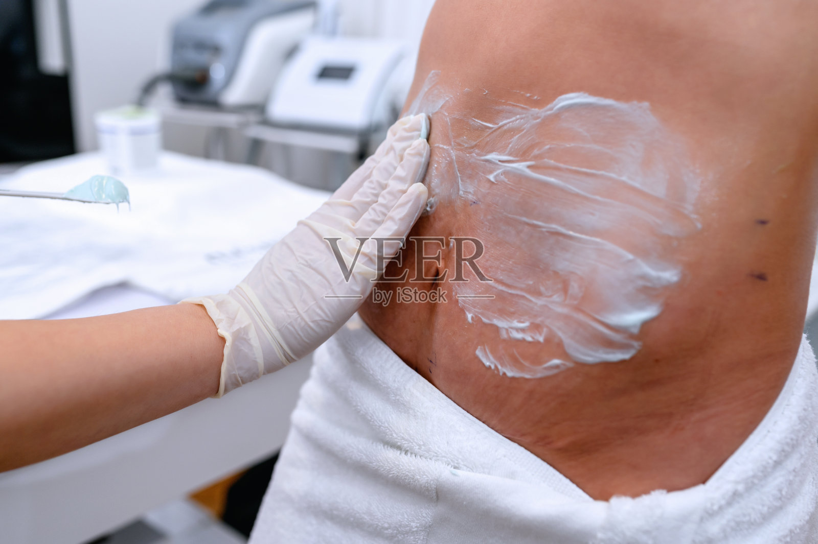 美容师将这种乳霜涂抹在有妊娠纹的腹部照片摄影图片