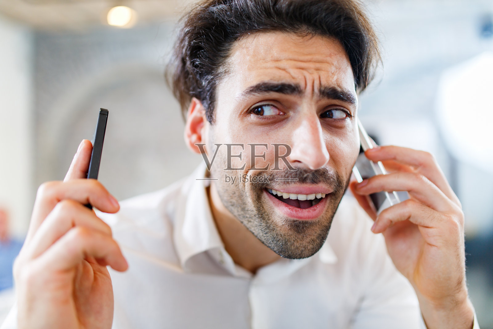 忙碌的生意人在办公室里用两部智能手机聊天。照片摄影图片