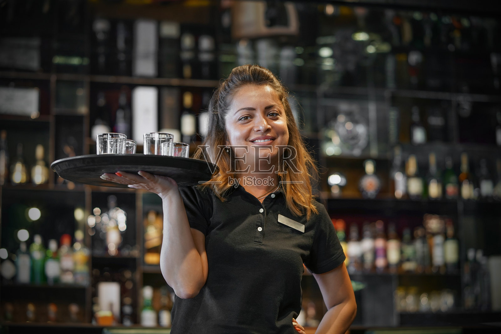 女服务员端着一只威士忌酒杯。照片摄影图片
