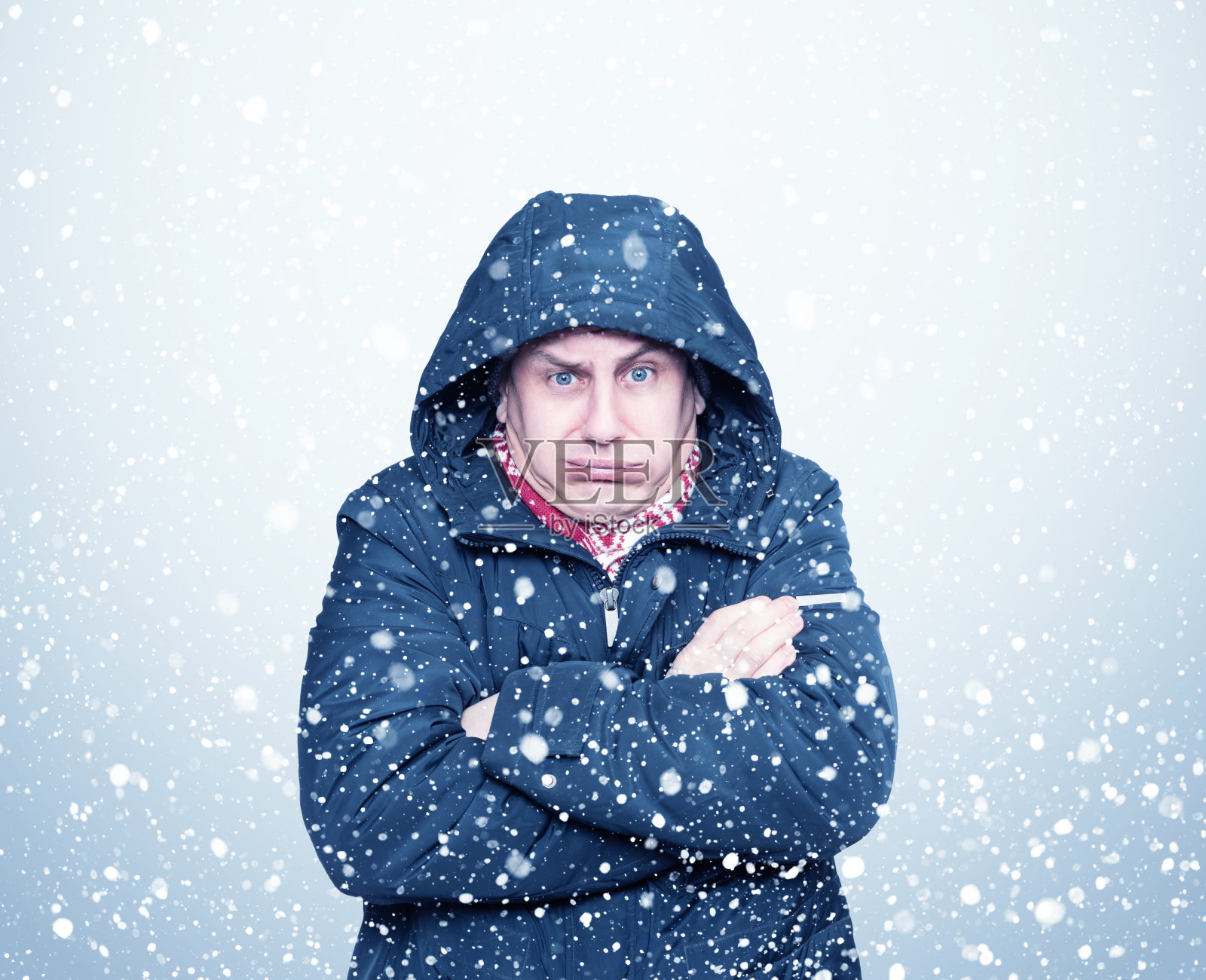 一个穿着夹克戴着兜帽的冰冻男子的肖像，冬天，周围在下雪照片摄影图片